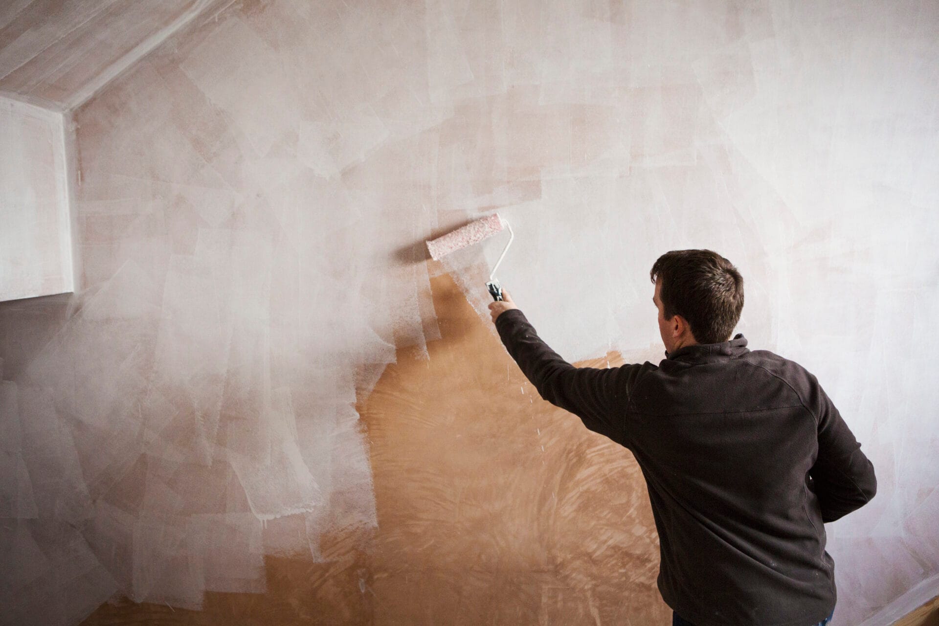 A builder, a painter holding a paint roll, painting a wall with white paint.,House renovation,England