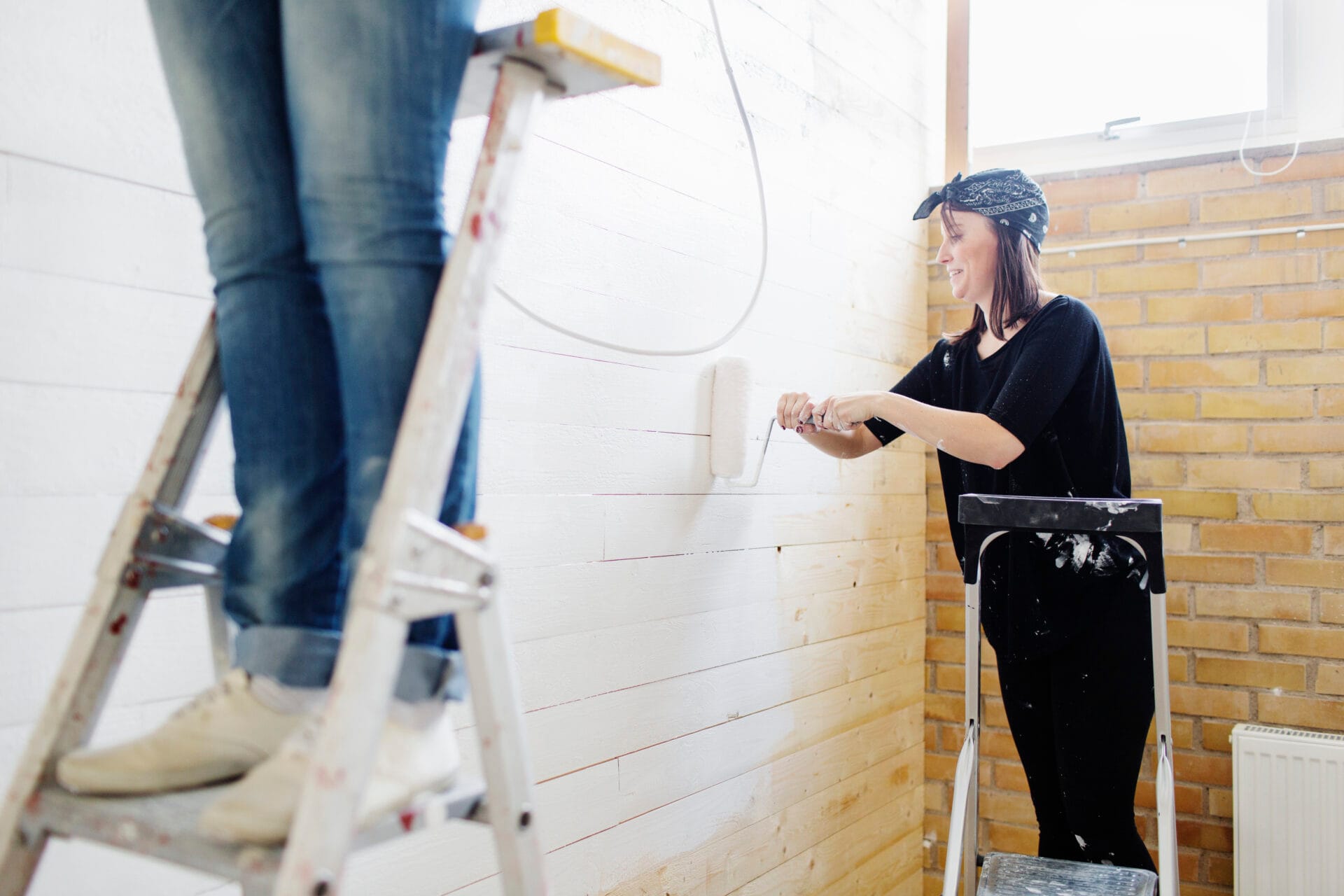 Woman painting wooden wall with paint roller